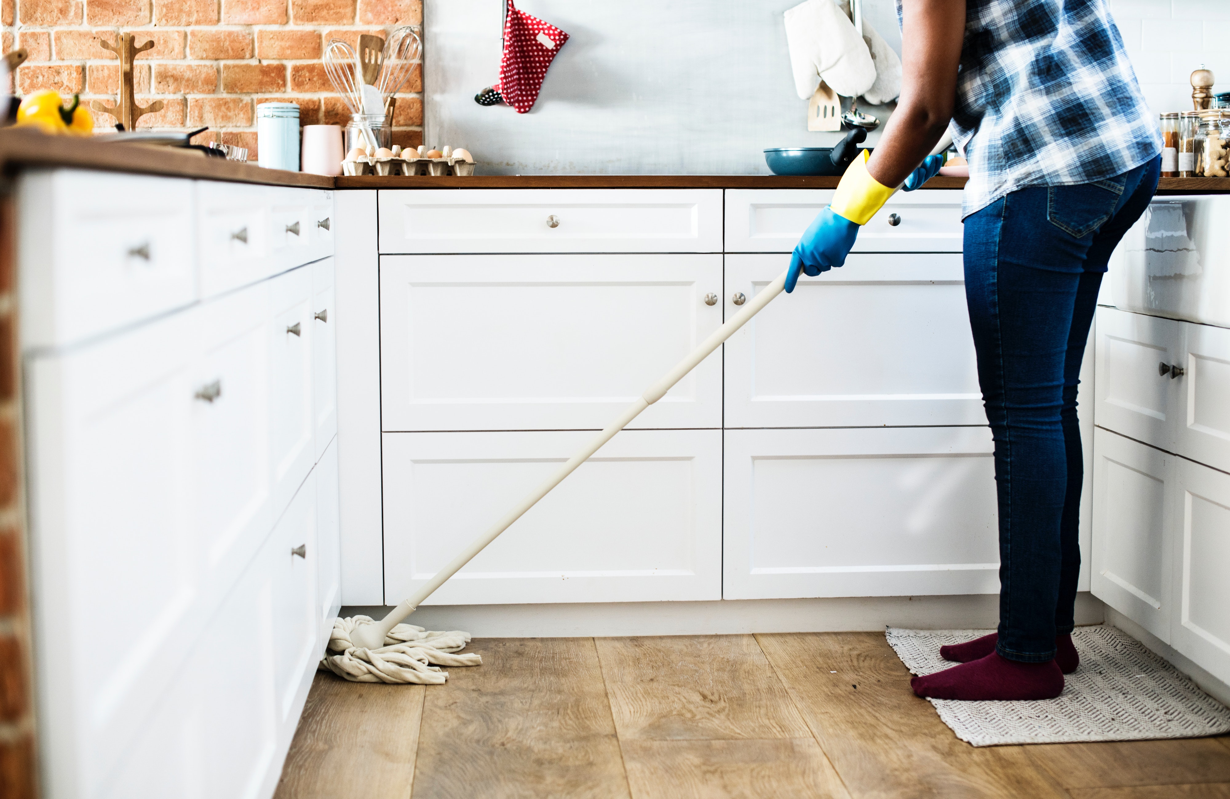 A woman cleans her tile floor carefully.
