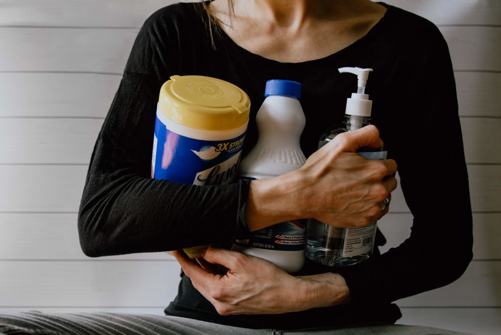 woman holding various cleaning supplies